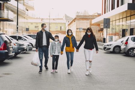 young-family-in-medical-masks-walking-along-parking-4127449
